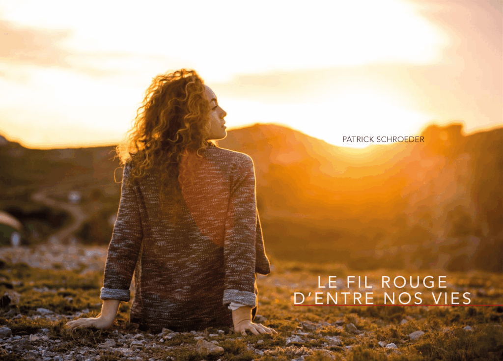 Une femme aux cheveux bouclés regarde le coucher de soleil, assise sur un sol rocailleux. Le texte indique : « Le fil rouge d’entre nos vies » – Patrick Schroeder.