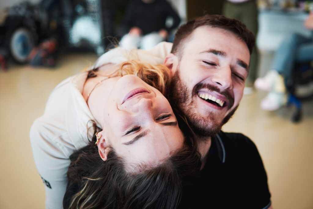 Une femme a la tête renversée en arrière sur l'épaule d'un homme, ils rient ensemble.